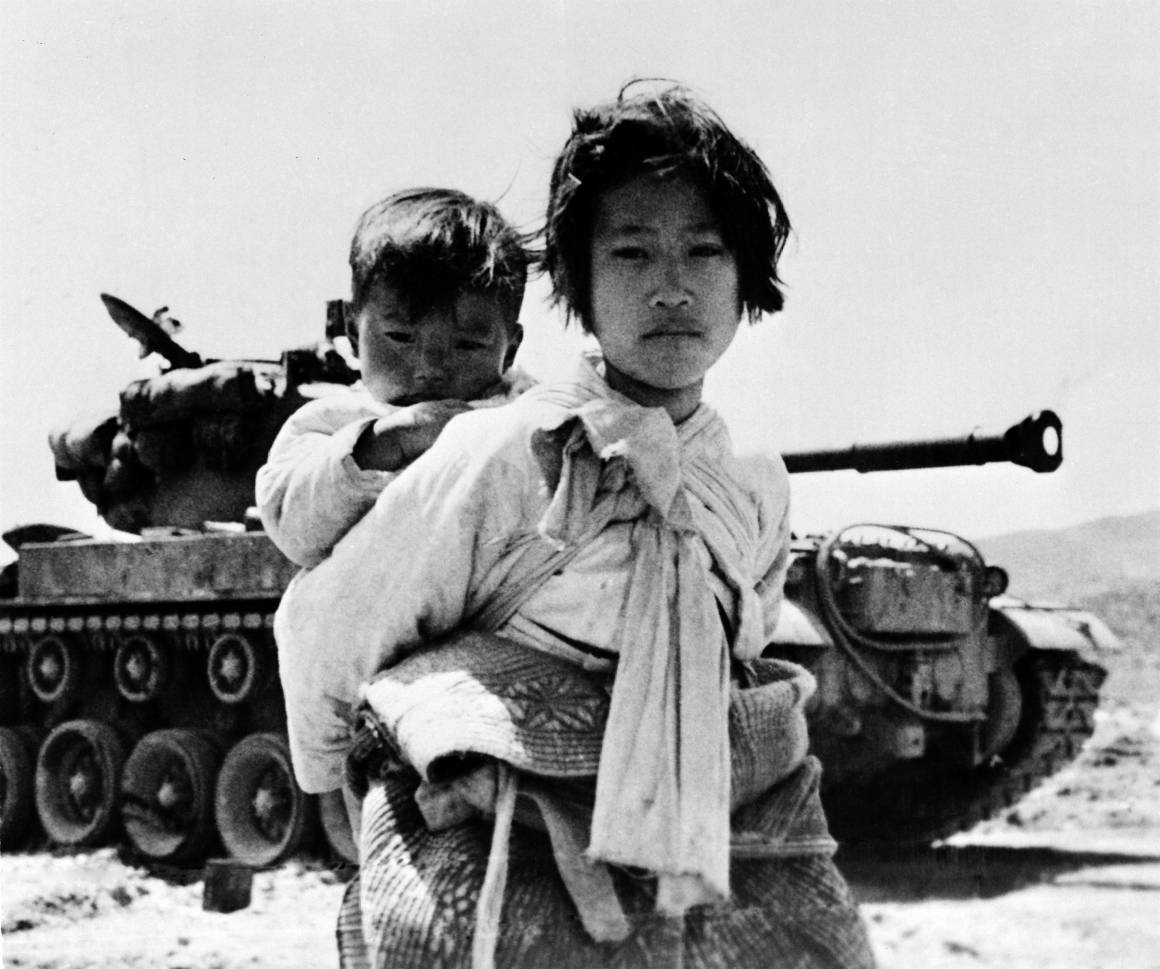 En ni år gammel pige bærer sin lillebror. Billedet af dette forældreløse søskendepar på flugt blevet taget under Koreakrigen, 9. juni 1951. Foto: UN Photo/United States Navy.