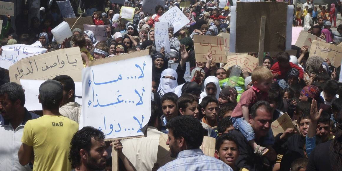 Folk samles i byen Nawa, nær Deraa i en af de første demonstrationer mod regimet i april 2011. På skiltet står der "Ingen vand, ingen medicin, ingen mad." (Foto: REUTERS / Handout).