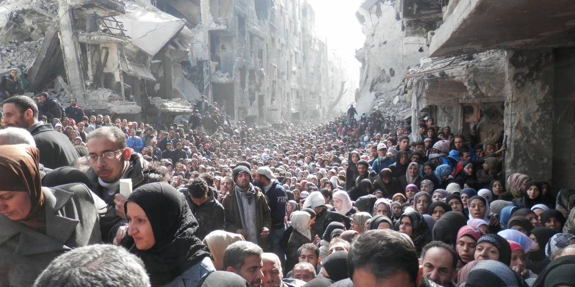 I den palæstinensiske flygtningelejr Yarmouk i Damaskus har adgangen til mad været meget begrænset under krigen. Befolkningen står i kø for at få madforsyninger fra FN, januar 2014 (Foto: Zuma Press / UNRWA).